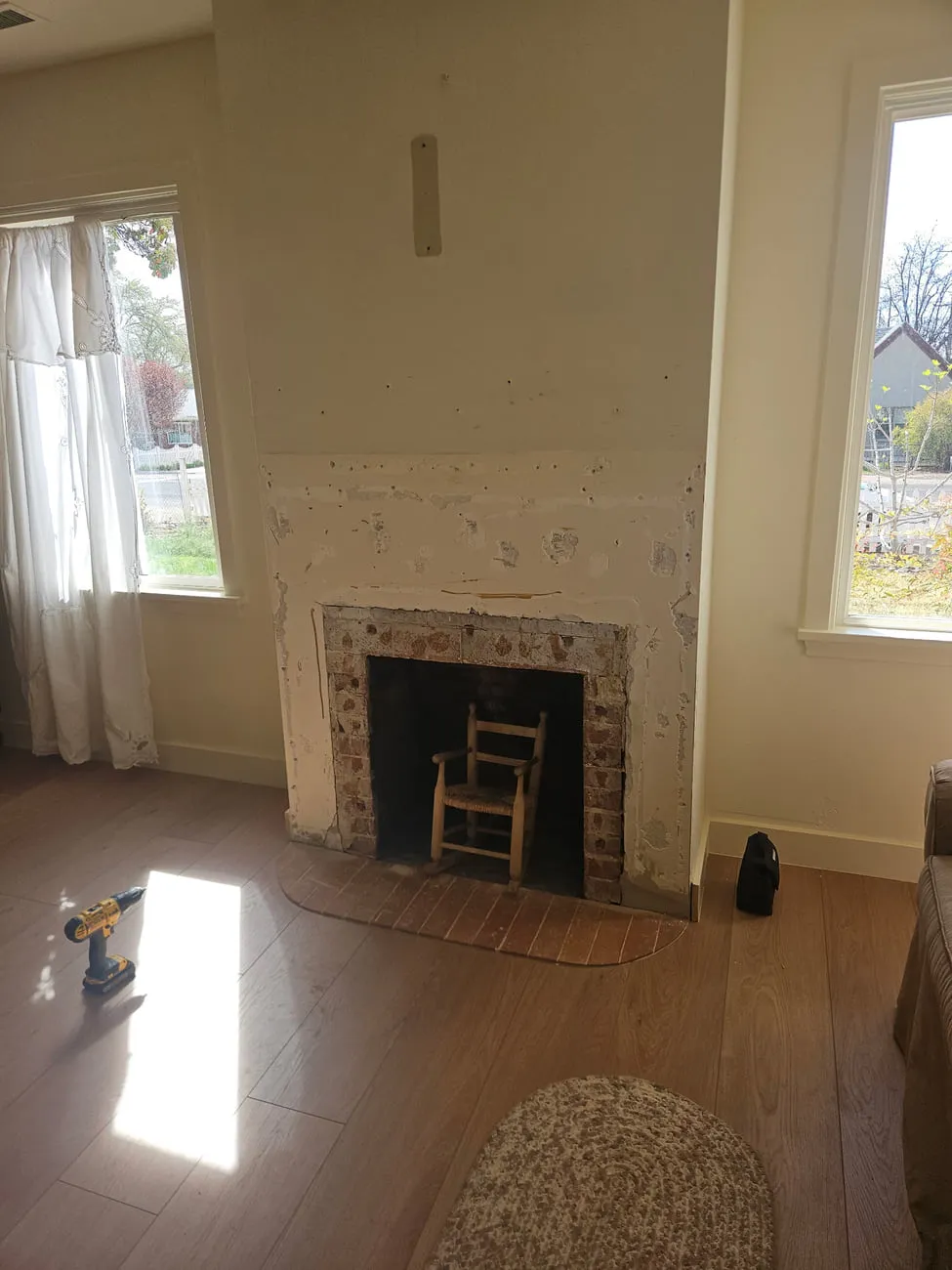 An old farmhouse brick firebox with the plaster around it stripped back and patched in blotches, no mantel, bare wall above