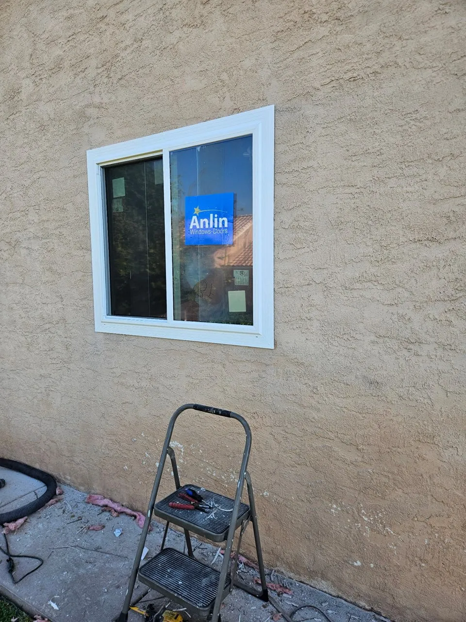 A new white vinyl sliding window set into tan stucco with fresh white trim around the frame