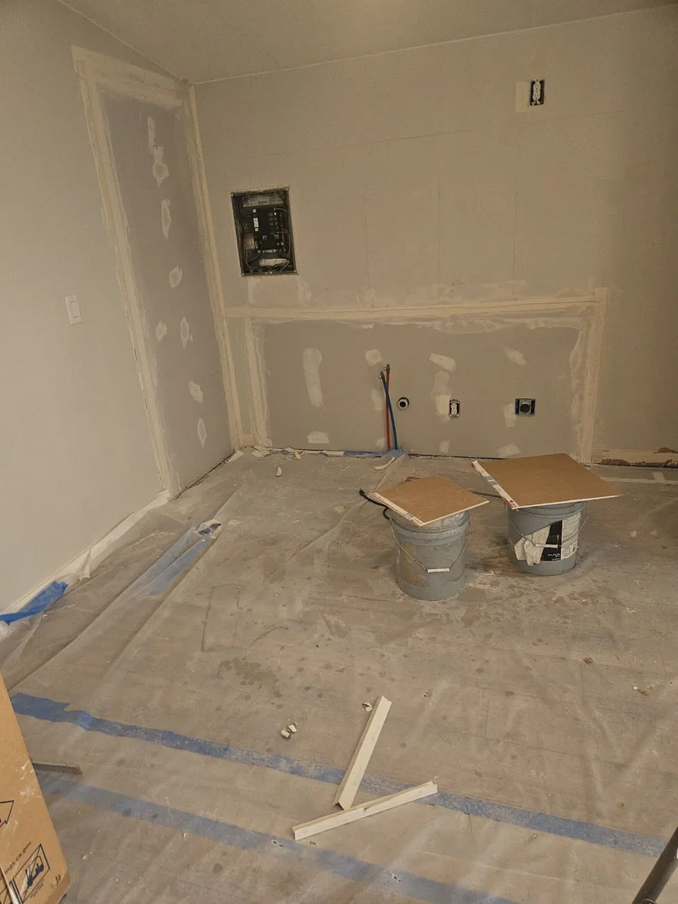 A room stripped for remodel with new drywall hung, taped and mudded over a former doorway opening