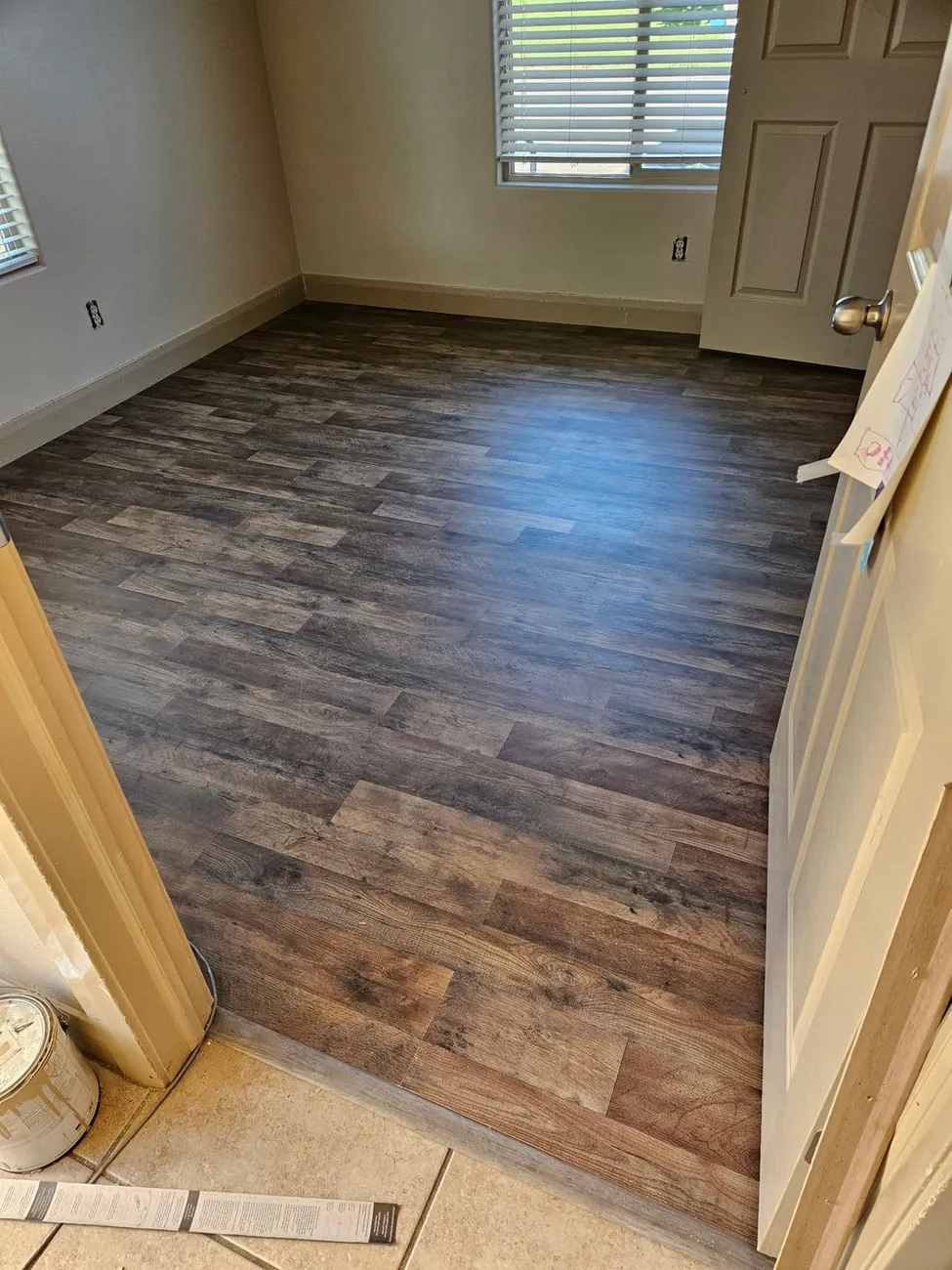 Dark rustic vinyl plank flooring finished up to a metal transition strip where it meets existing tile