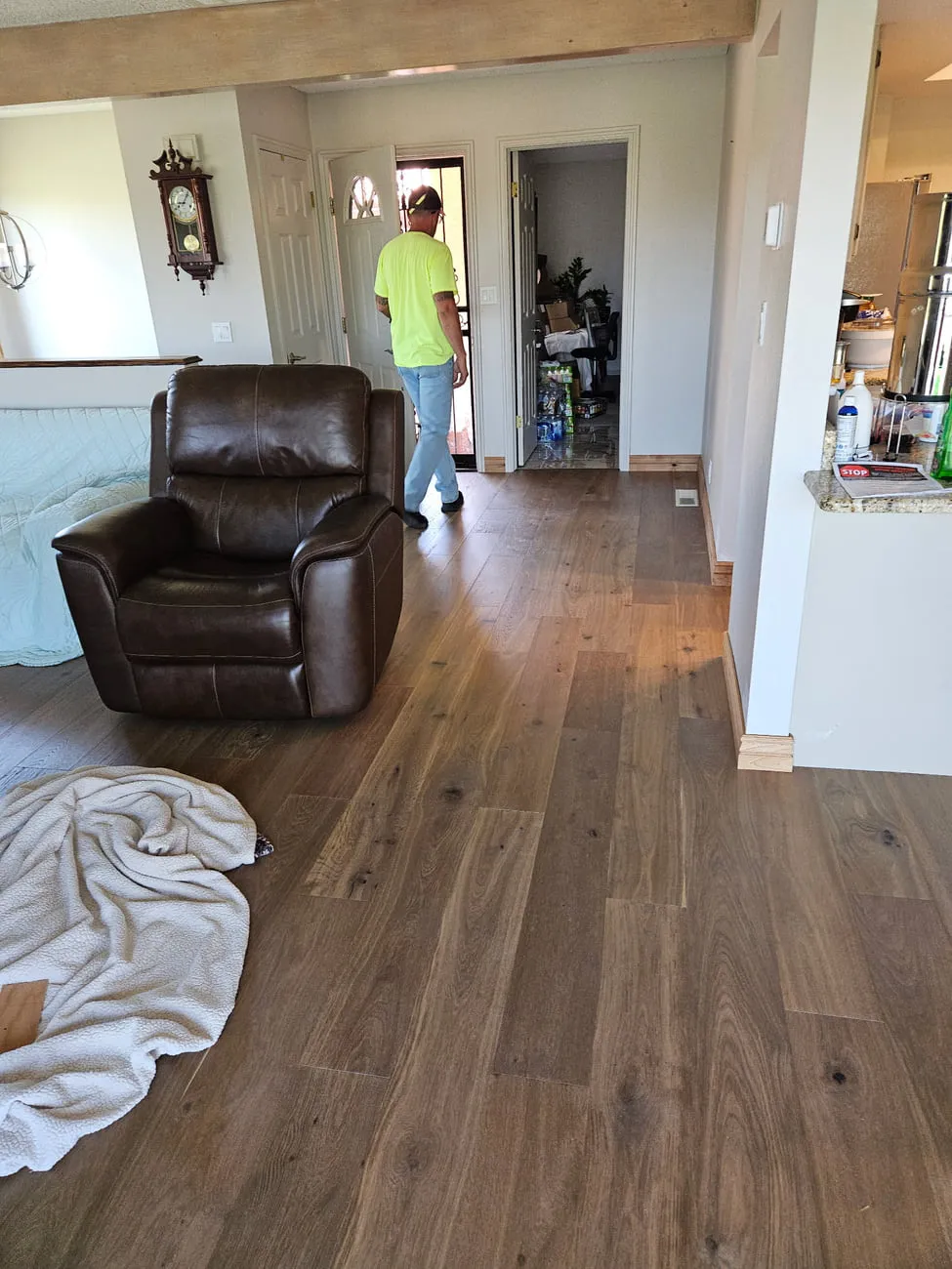 A living room with wide dark plank flooring complete and new base shoe installed under an exposed beam ceiling
